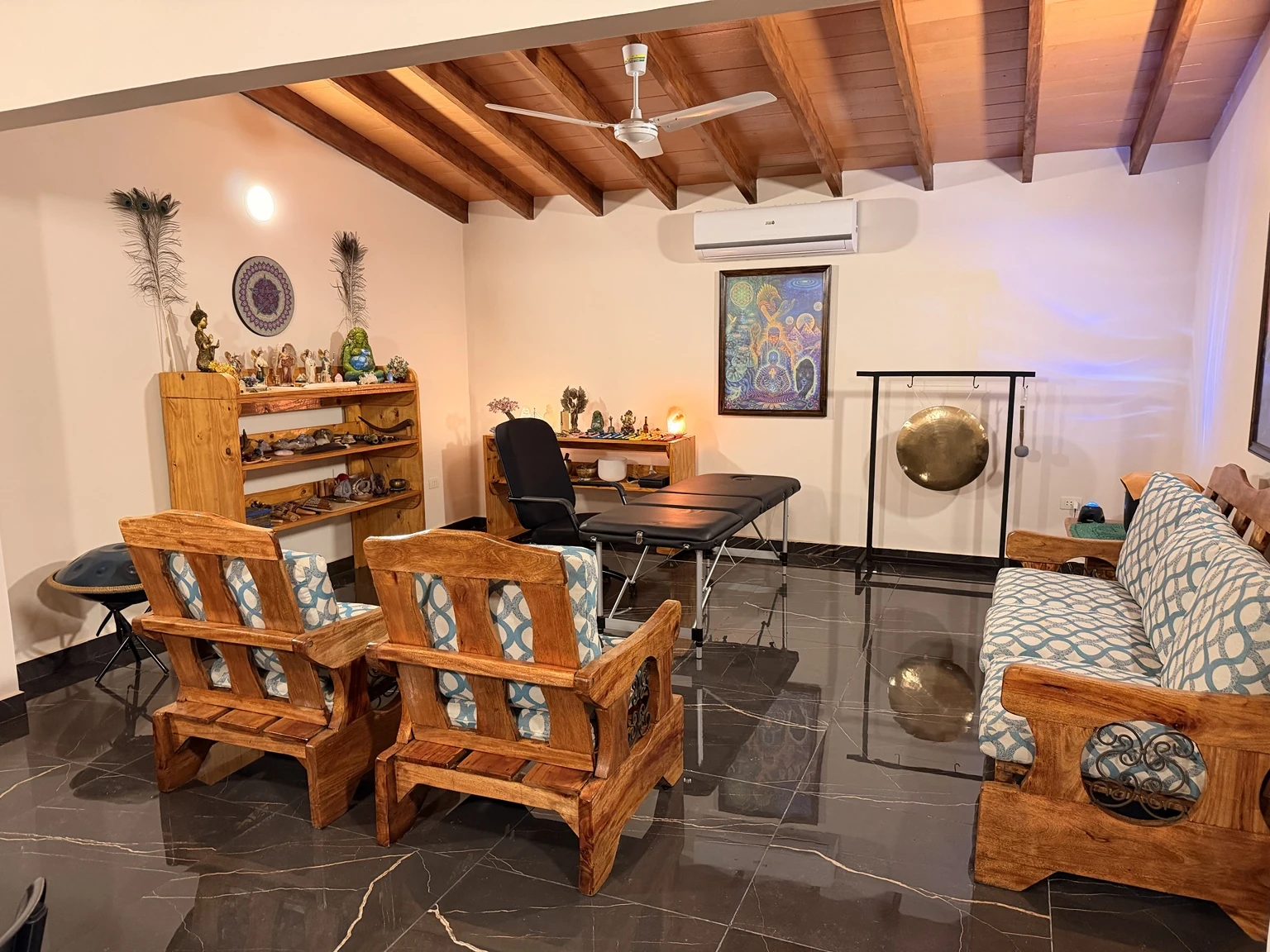 Interior del consultorio con la camilla, el gong, los instrumentos y los asientos de madera.